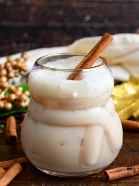 rumChata cocktail with a cinnamon sick in the glass on a wood surface.