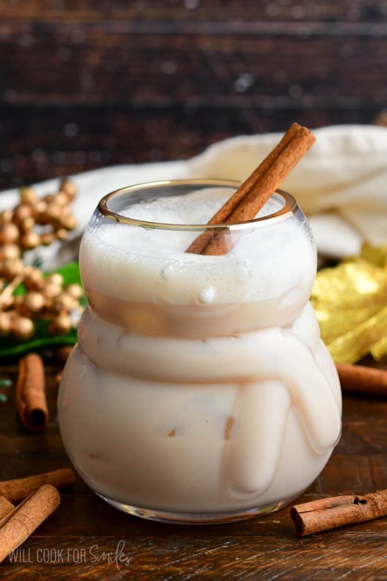 rumChata cocktail with a cinnamon sick in the glass on a wood surface.