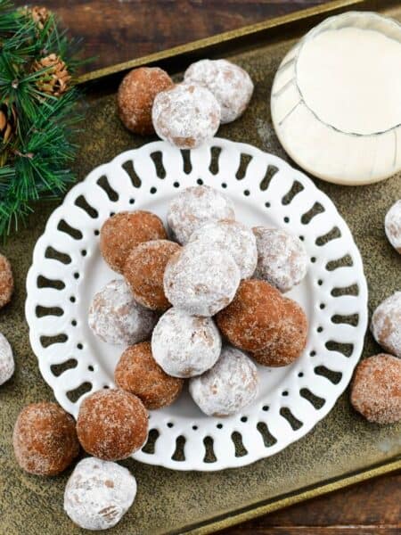 Rumchata rum balls on a white plate that is sitting on a gold tray.