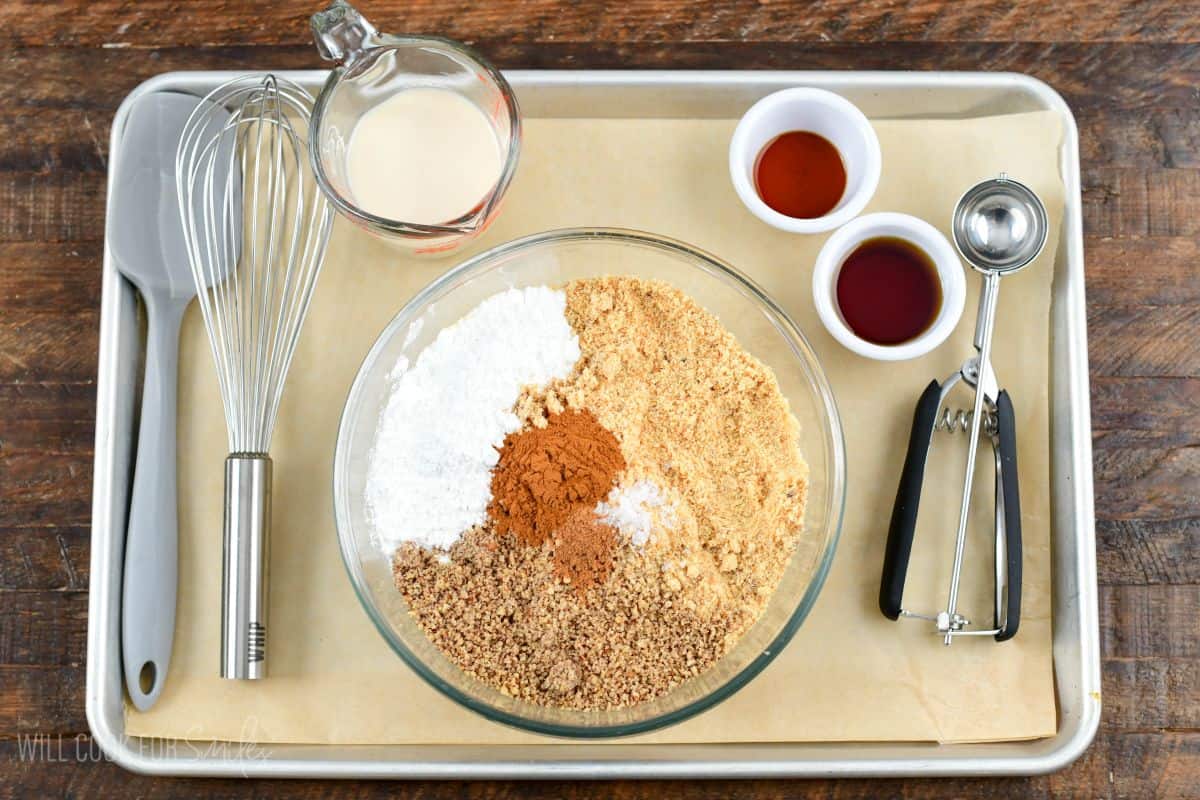 Rumchata rum balls dry ingredients in a glass bowl, wet ingredients in separate bowl with the tools needed to make them.