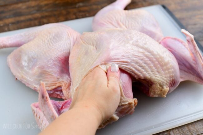 separating the skin from the turkey breast using a hand.
