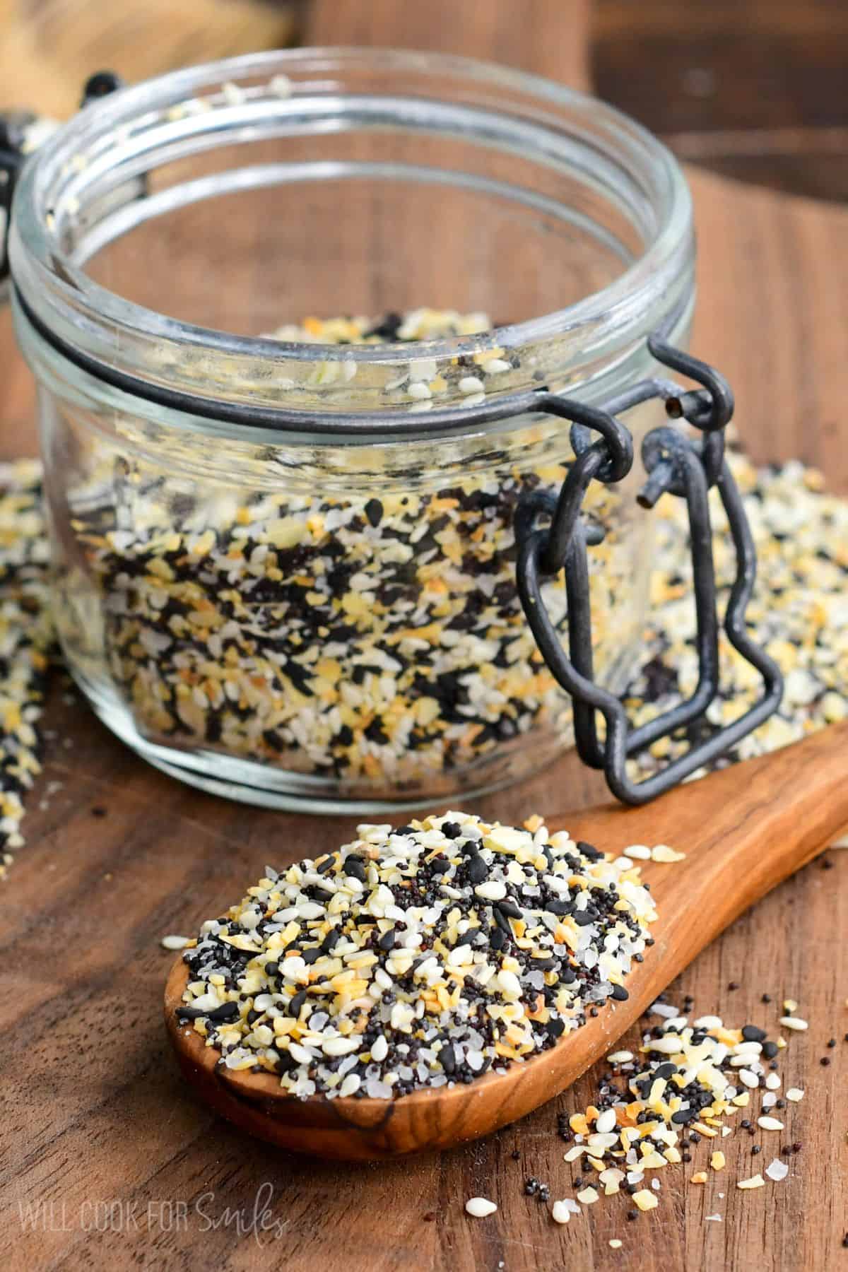 a spoon full of everything bagel seasoning next to the glass jar.