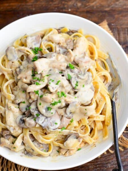 family recipe restaurant style creamy chicken stroganoff over pasta in a bowl.