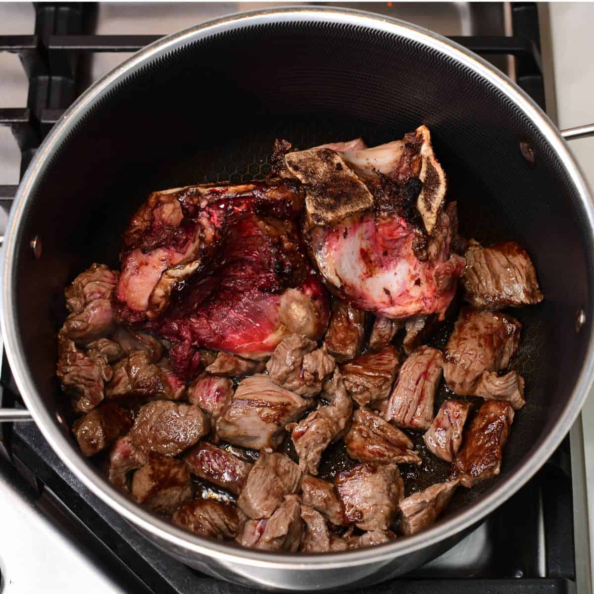 searing large beef bones and beef stew meat in the pot for the soup.