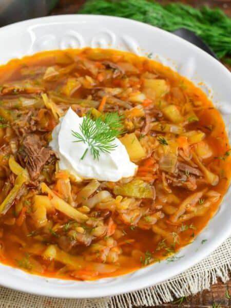 Russian beef and cabbage soup (shchi) in a bowl with a dollop of sour cream and dill.