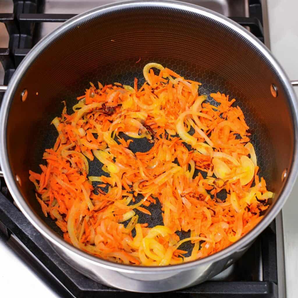sautéing onions and carrots until golden brown in a pot.