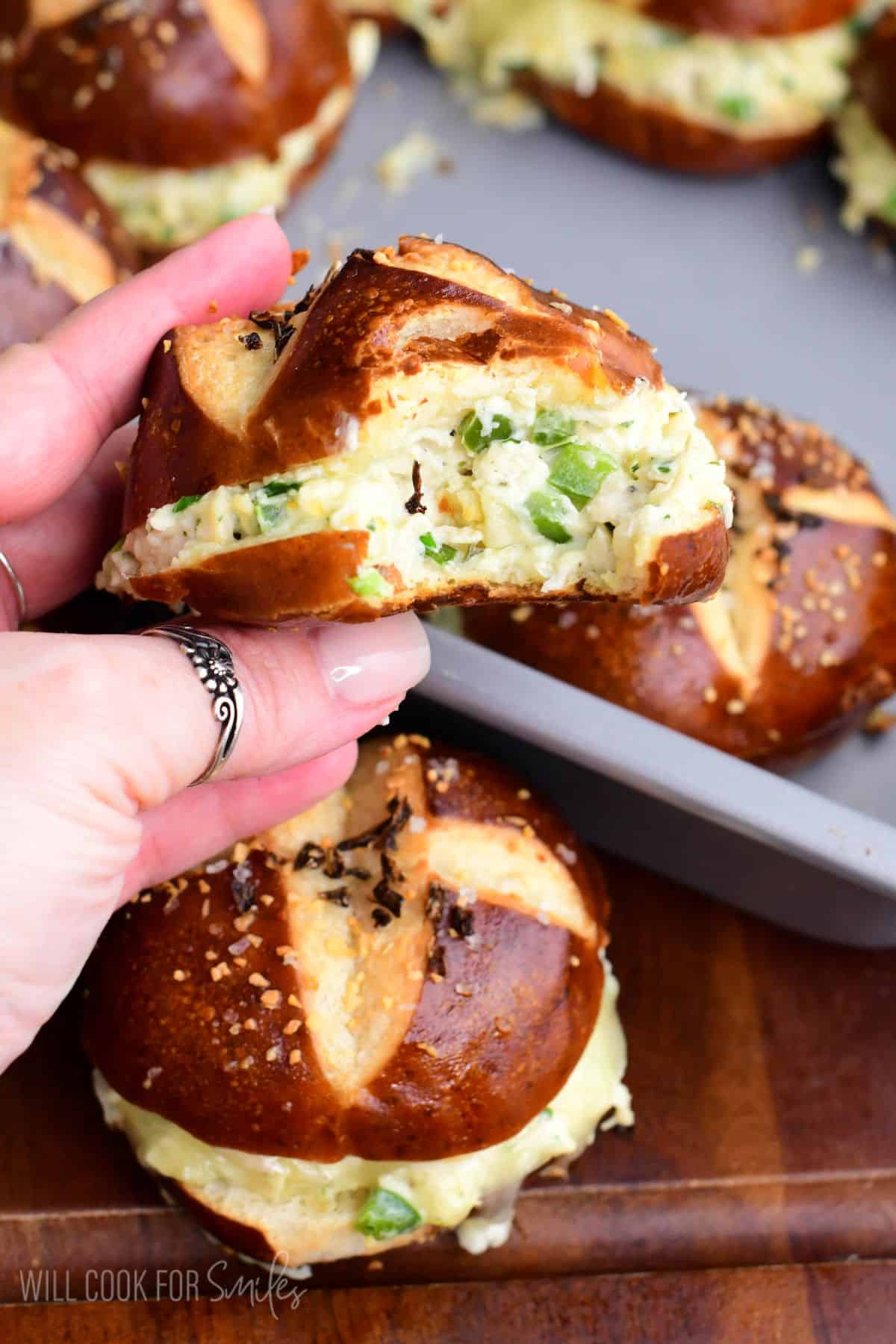 A jalapeño ranch chicken slider on a pretzel bun with a bite taken out, showing the creamy chicken and jalapeño filling.