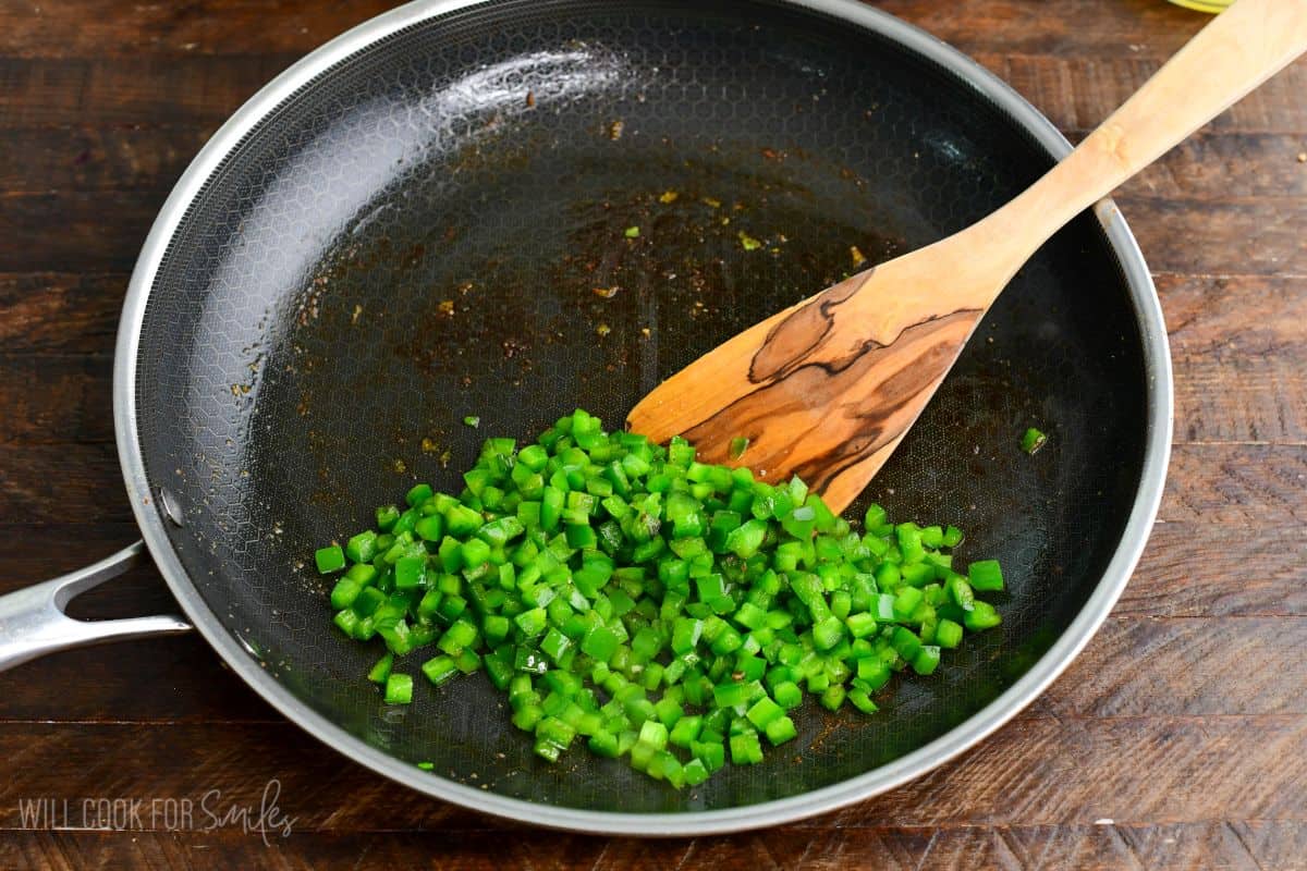 Diced jalapeños sautéing in a skillet after cooking the chicken for jalapeño ranch chicken sliders.