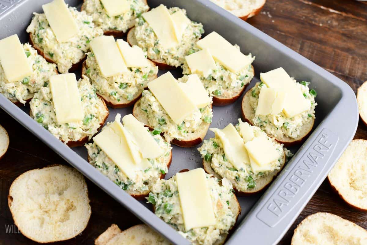 Jalapeño ranch chicken slider buns filled with creamy chicken mixture and topped with sliced cheese before baking.