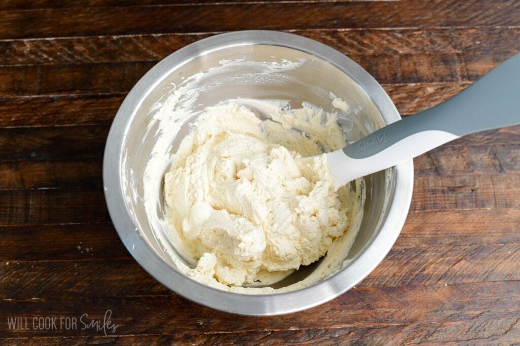 No-bake cheesecake filling mixed in a bowl with a spatula for cherry cheesecake parfaits.