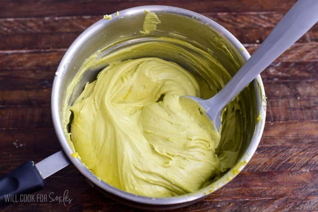 Mascarpone cheese folded into pistachio custard in a saucepan, creating a smooth, creamy pistachio mascarpone mixture.