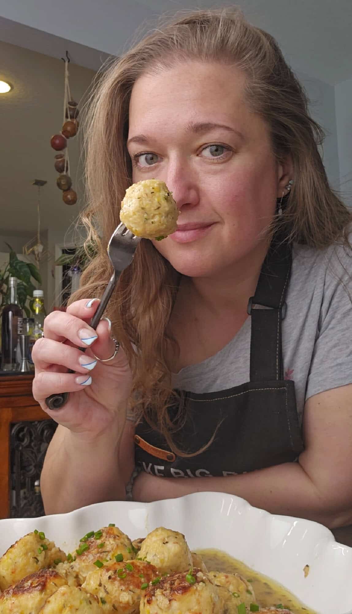 Lyuba from will cook for smiles holding a shrimp meatball on a fork.