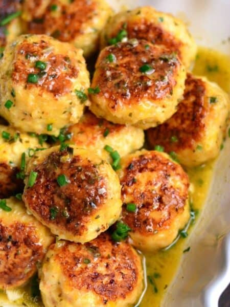several juicy shrimp meatballs and flavorful scampi sauce in a serving bowl.