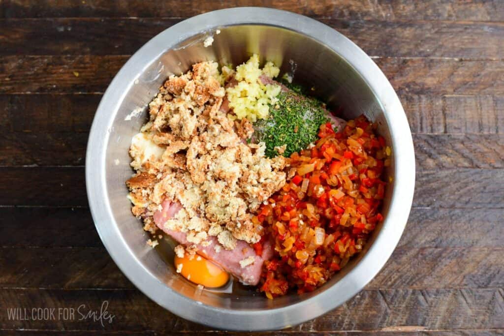 Ground turkey, sautéed peppers and onions, egg, breadcrumbs, garlic, and herbs combined in a mixing bowl to prepare turkey meatloaf.