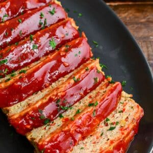 juicy and tender turkey meatloaf with honey balsamic ketchup glaze sliced on a black platter.