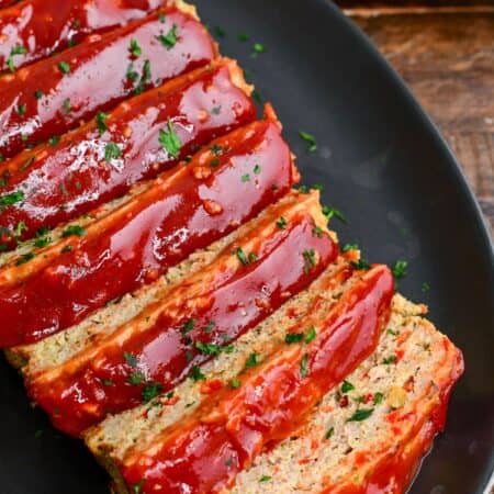 juicy and tender turkey meatloaf with honey balsamic ketchup glaze sliced on a black platter.
