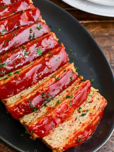 juicy and tender turkey meatloaf with honey balsamic ketchup glaze sliced on a black platter.
