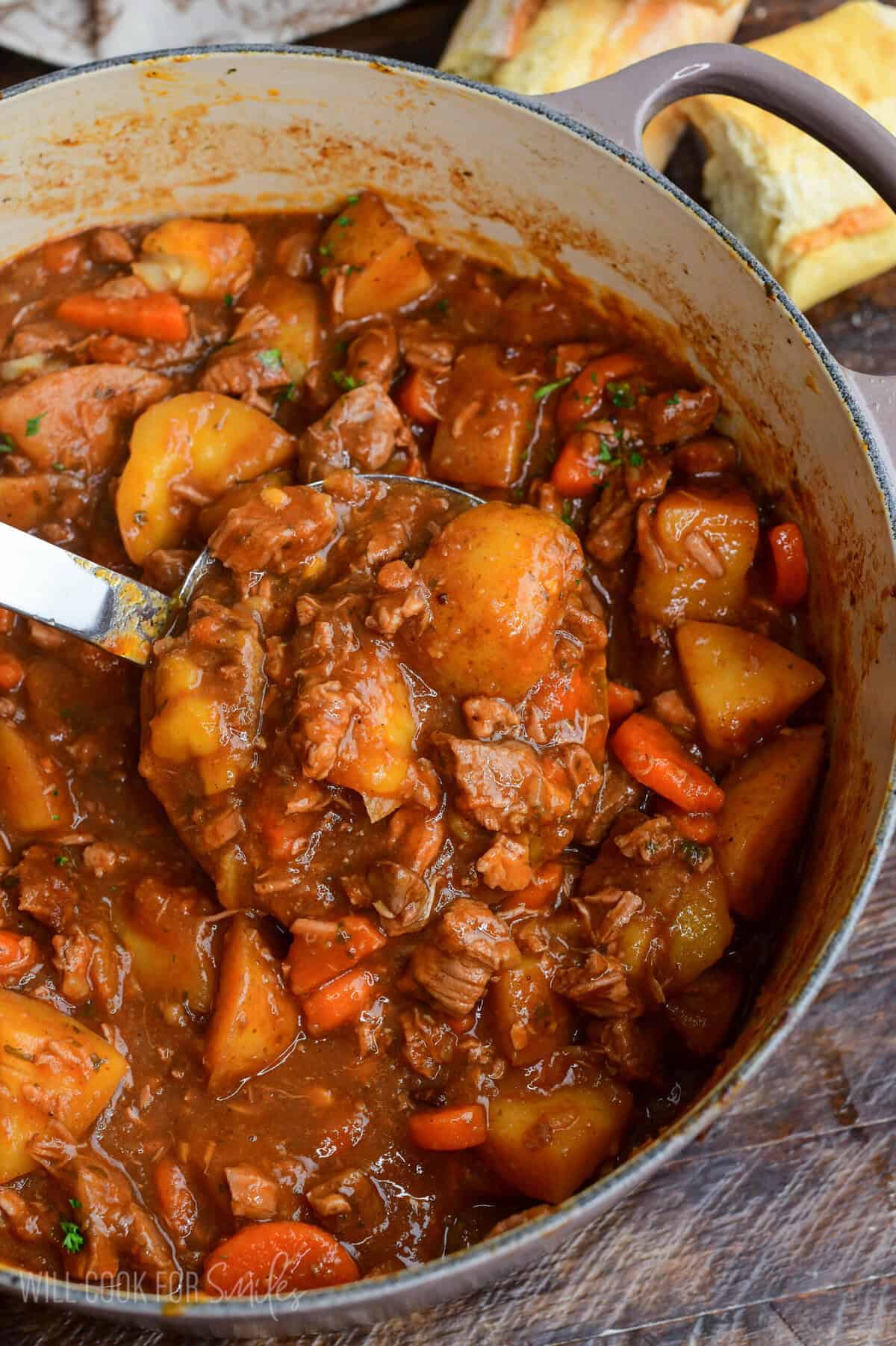 Pot of traditional Irish lamb stew with tender lamb, potatoes, and carrots in a thick savory broth with a ladle scooping the stew.