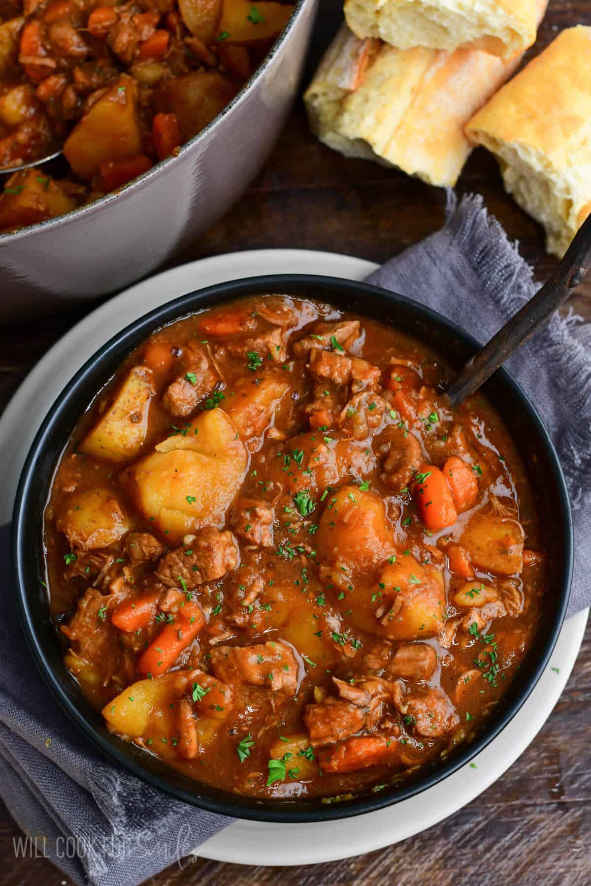 Bowl of hearty Irish lamb stew with tender lamb, potatoes, and carrots in a rich savory broth, garnished with parsley and served with crusty bread.