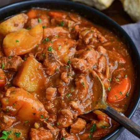 Close-up of Irish lamb stew with tender lamb, potatoes, and carrots in a rich savory broth with a spoon scooping the stew.