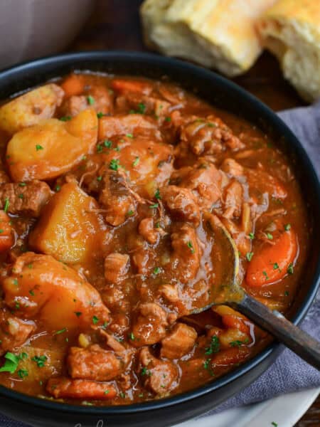 Close-up of Irish lamb stew with tender lamb, potatoes, and carrots in a rich savory broth with a spoon scooping the stew.