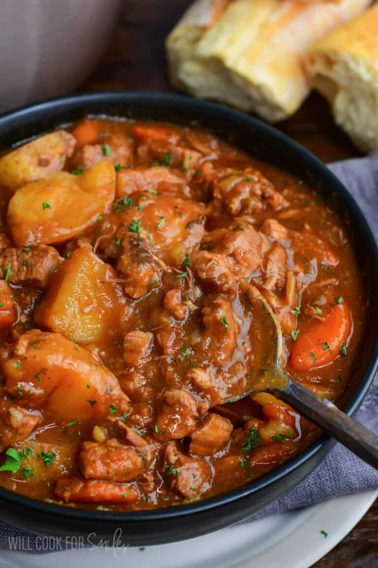 Close-up of Irish lamb stew with tender lamb, potatoes, and carrots in a rich savory broth with a spoon scooping the stew.