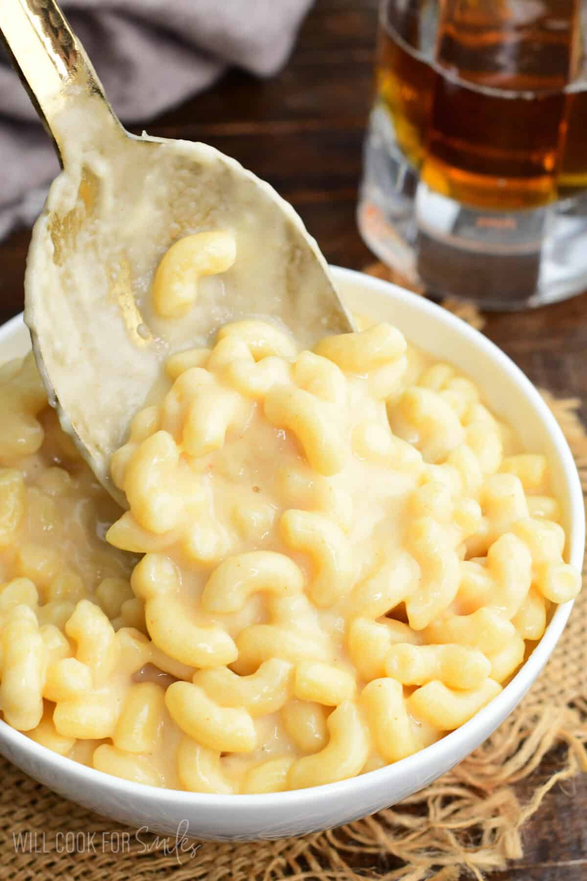 Creamy homemade beer macaroni and cheese in a bowl with a spoon lifting cheesy elbow pasta coated in rich beer cheese sauce.