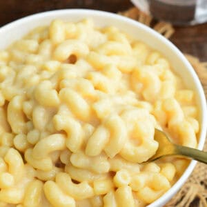 Bowl of creamy beer macaroni and cheese with a spoon scooping cheesy elbow pasta.
