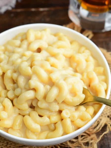 Bowl of creamy beer macaroni and cheese with a spoon scooping cheesy elbow pasta.