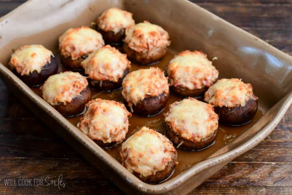 Baked Reuben stuffed mushrooms in a casserole dish with melted golden Swiss cheese on top.