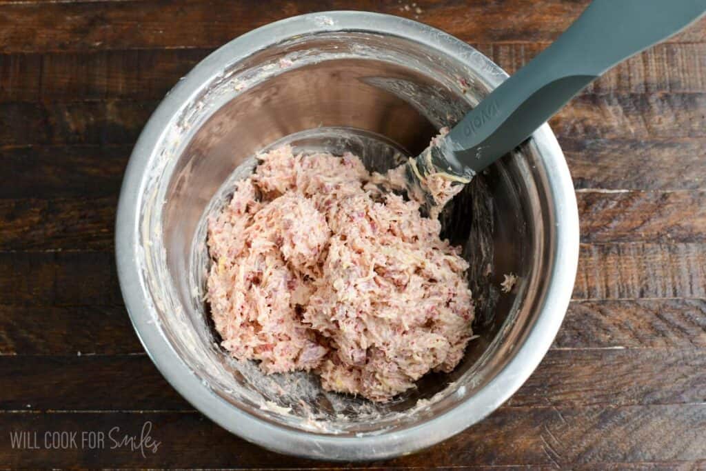 Mixing bowl with chopped corned beef, shredded Swiss cheese, sauerkraut, cream cheese, and dressing for Reuben stuffed mushrooms.