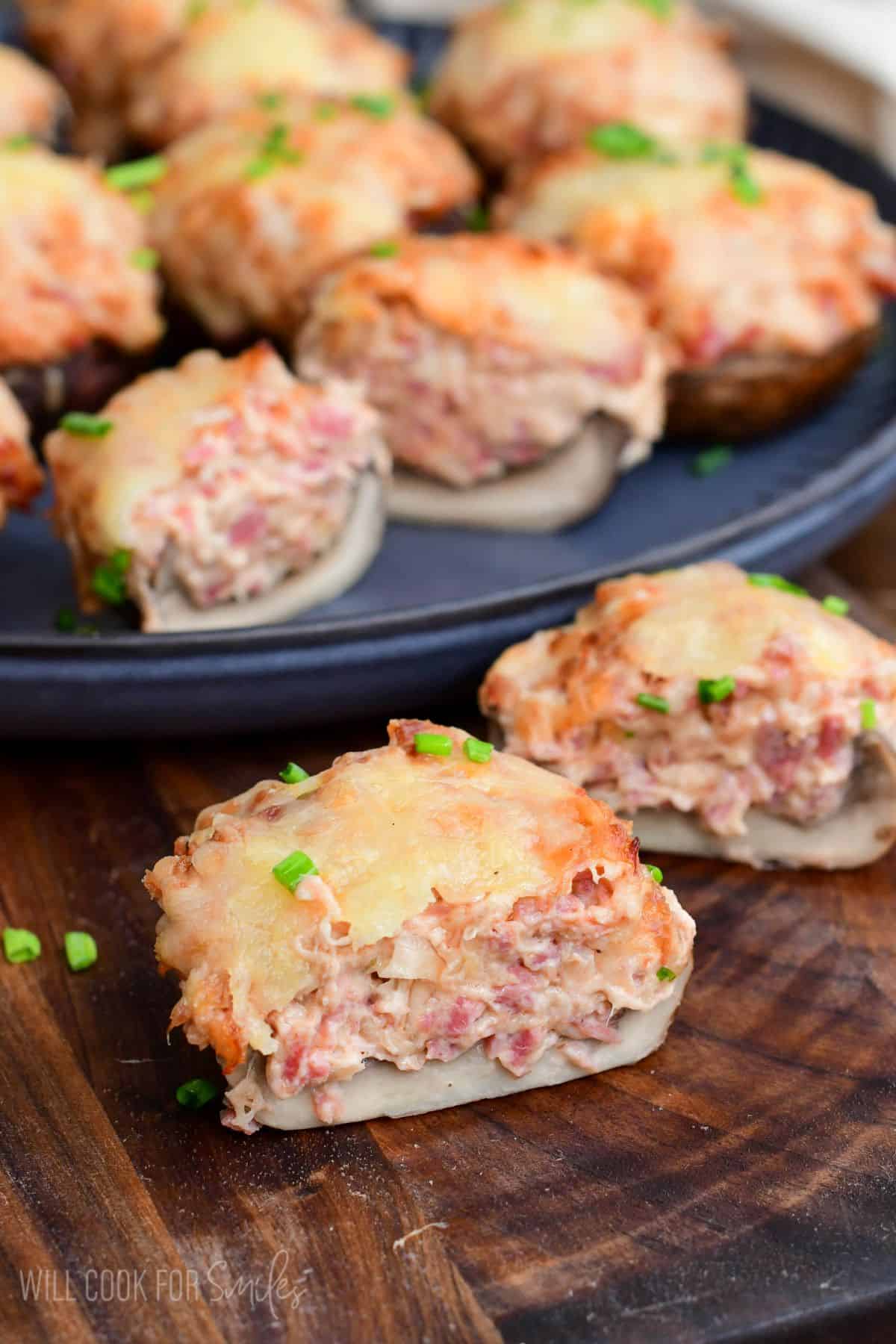 Reuben stuffed mushroom cut in half showing the creamy corned beef filling and melted Swiss cheese, with more mushrooms on a platter in the background.