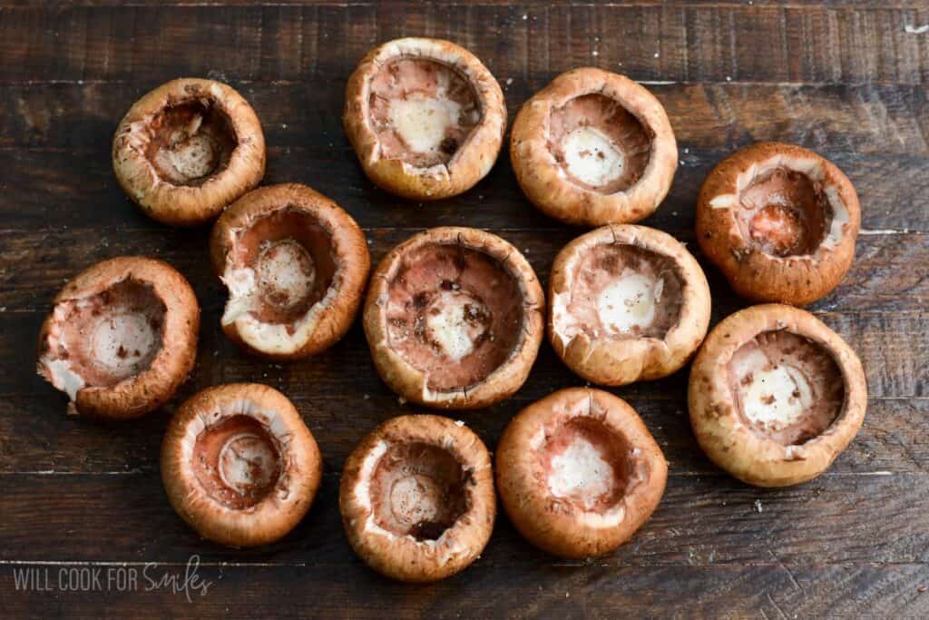 Hollowed out mushroom caps arranged on a wooden surface, prepared for stuffing.