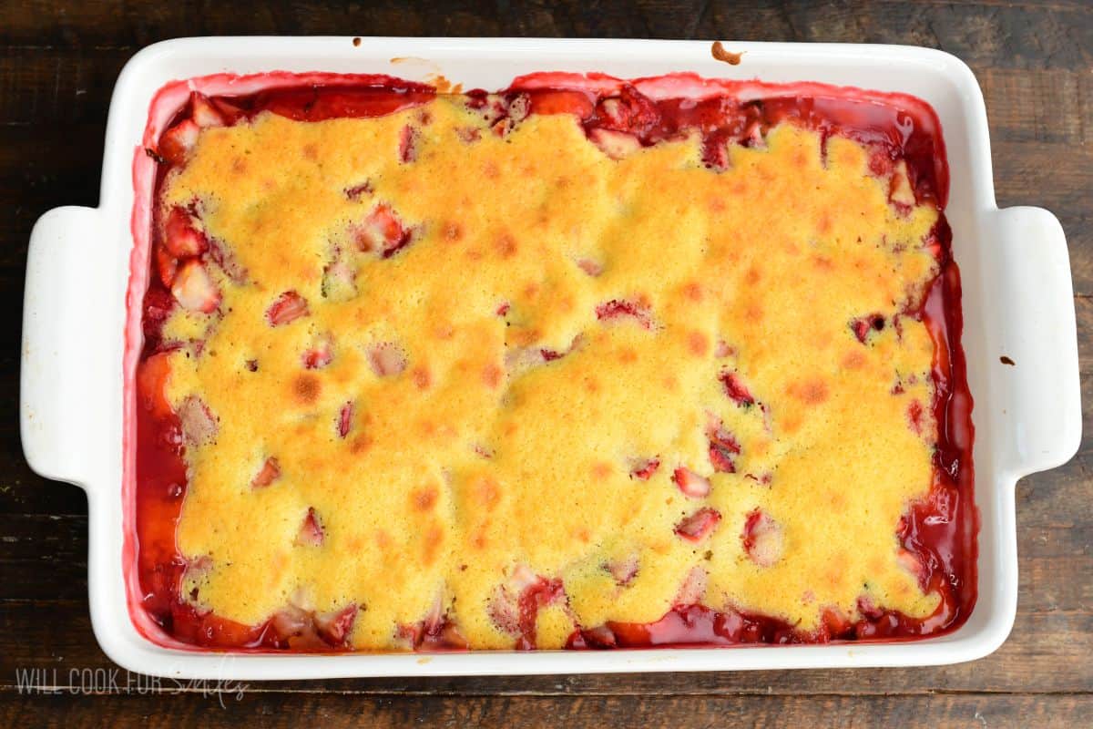 Freshly baked strawberry basil cobbler in a baking dish with golden crust and bubbling fruit filling around the edges.