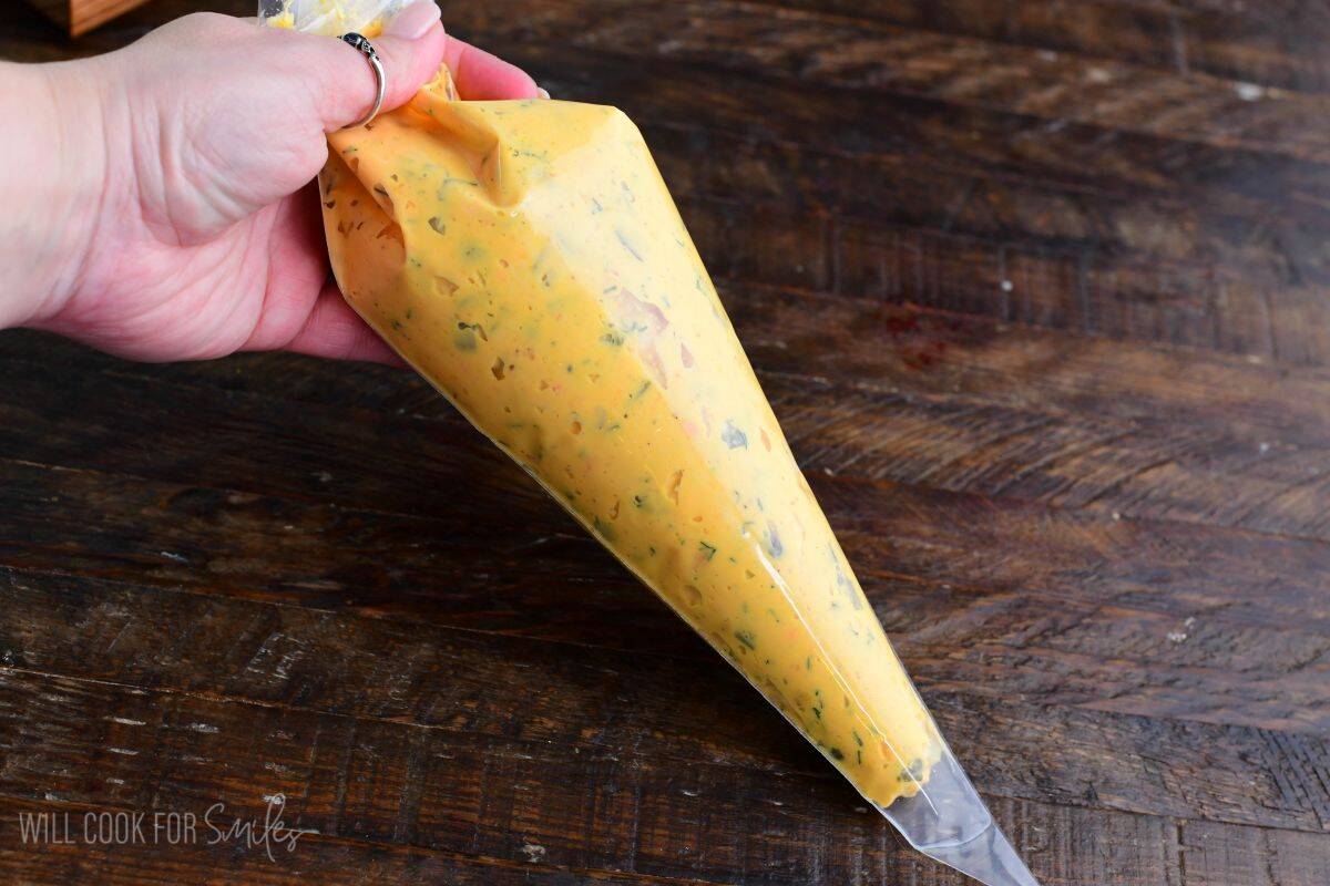 Deviled egg filling with dill and pickles in a piping bag, ready to be piped into egg whites.