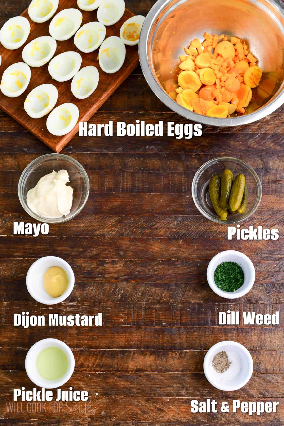 labeled ingredients for Dill Pickle Deviled Eggs on a wood surface.