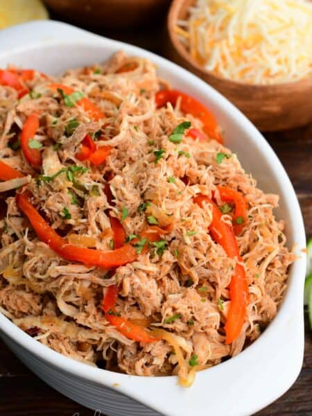 shredded moist and tender salsa chicken mixed with caramelized vegetables in the serving dish.
