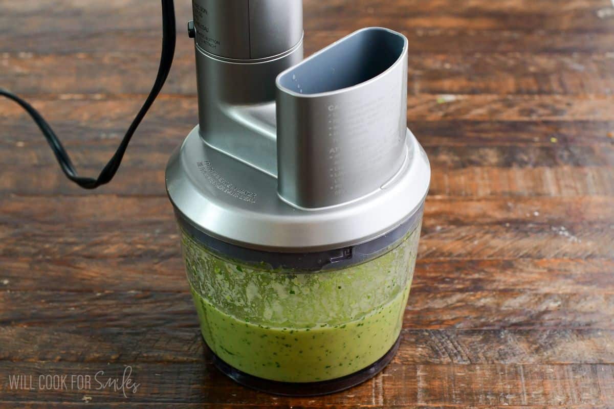 Blended avocado dressing in a small food processor.