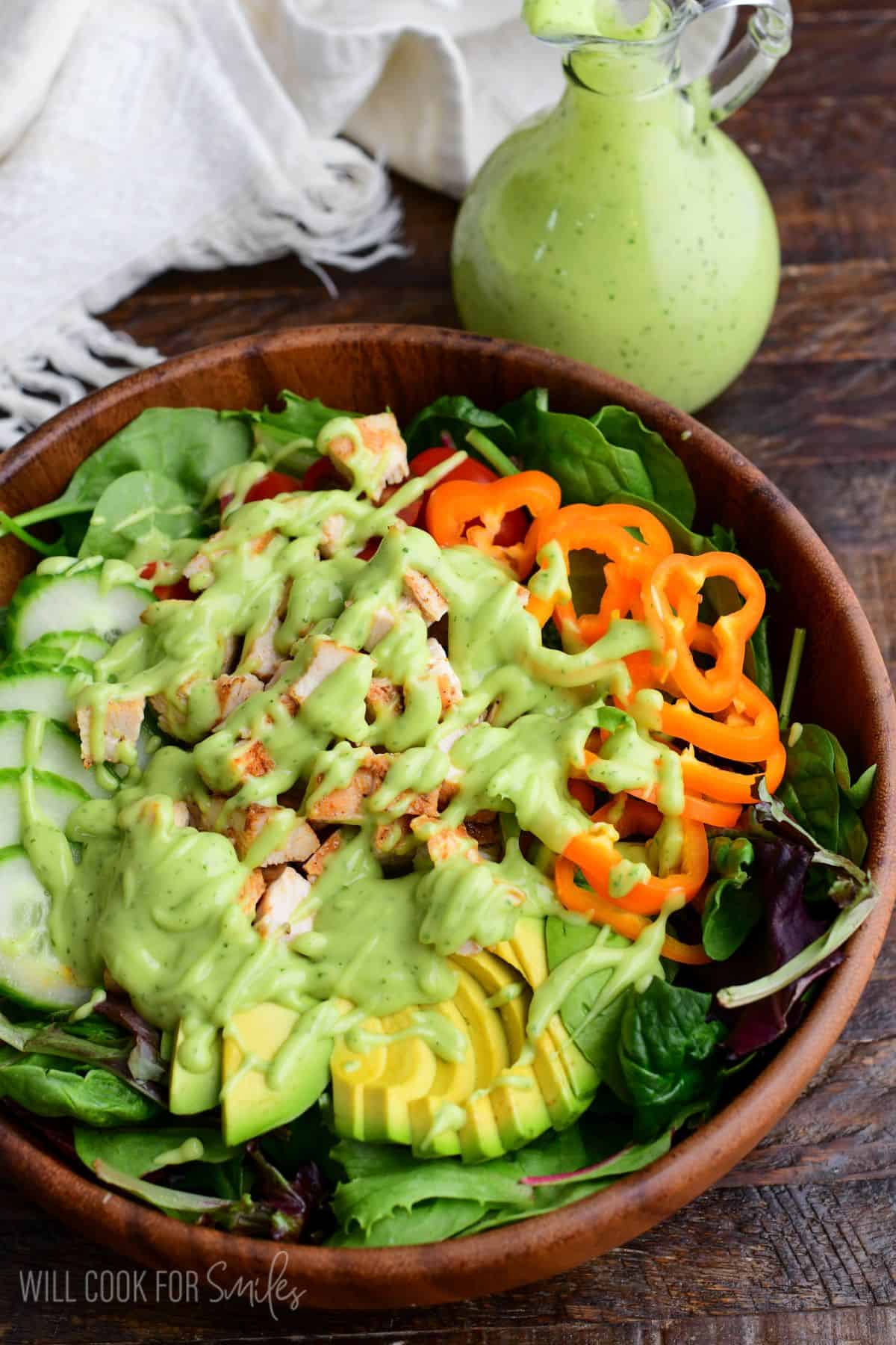 a salad with veggies and chicken topped with a rich avocado dressing.