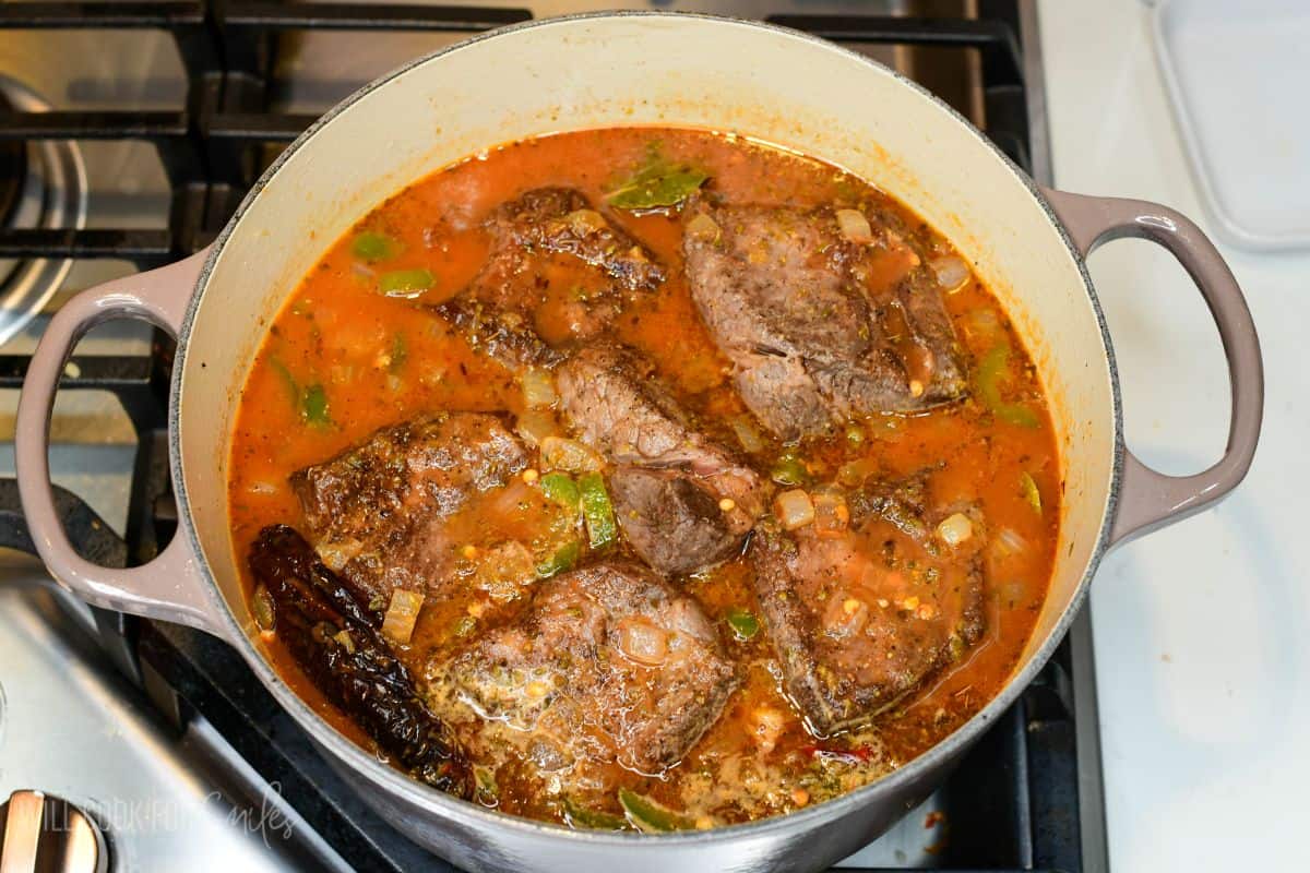 seared short ribs nestled back into the chili sauce in the Dutch oven before braising.