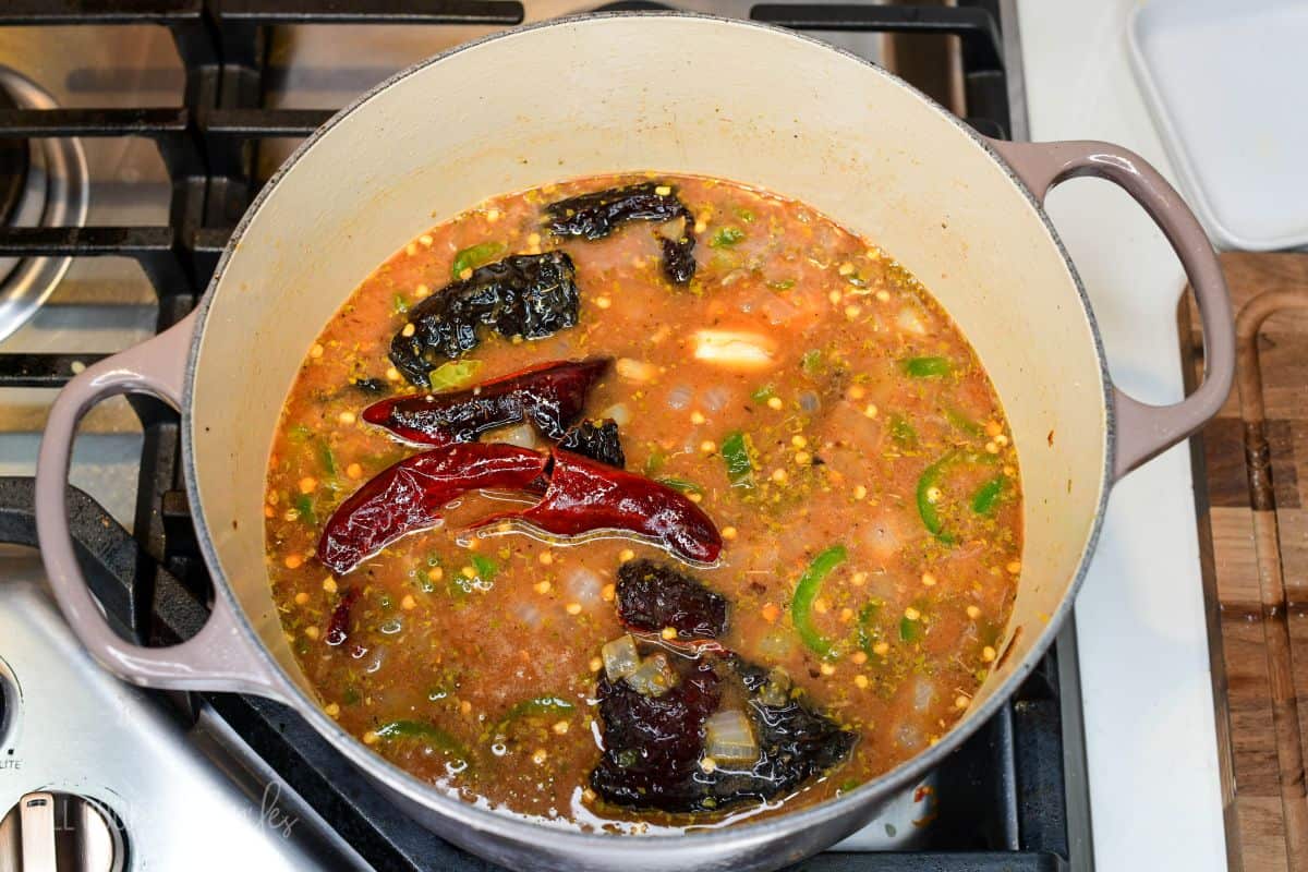 sauce ingredients to make Mexican braised short ribs in a Dutch oven including dried chili peppers, veggies, broth and seasoning.