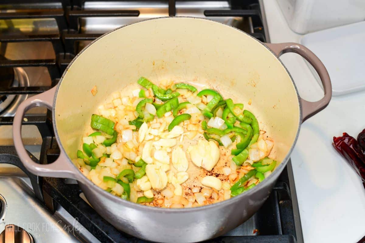 sauteed onions and jalapenos with garlic cloves searing in the Dutch oven.
