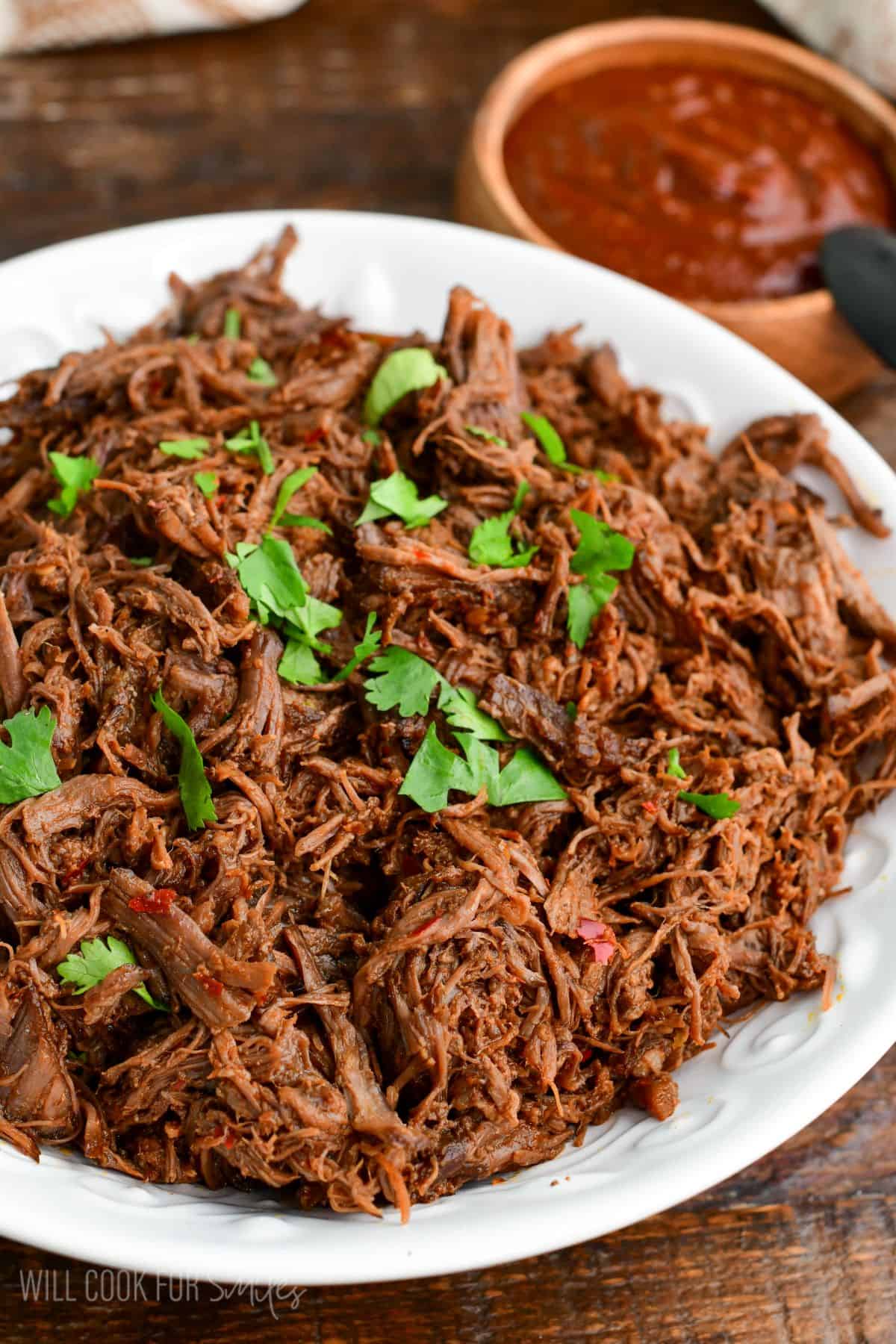 tender Mexican braised short ribs shredded in a bowl topped with cilantro.