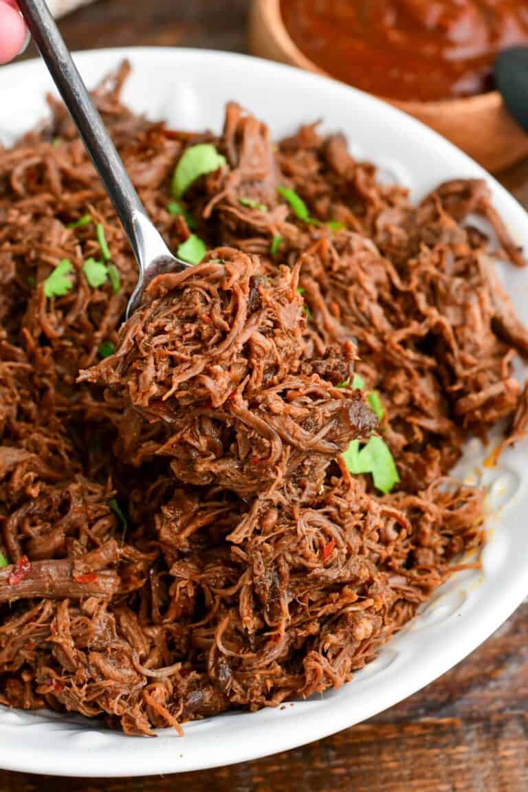 scooping out some tender shredded short ribs meat mixed with chili sauce out of a bowl.