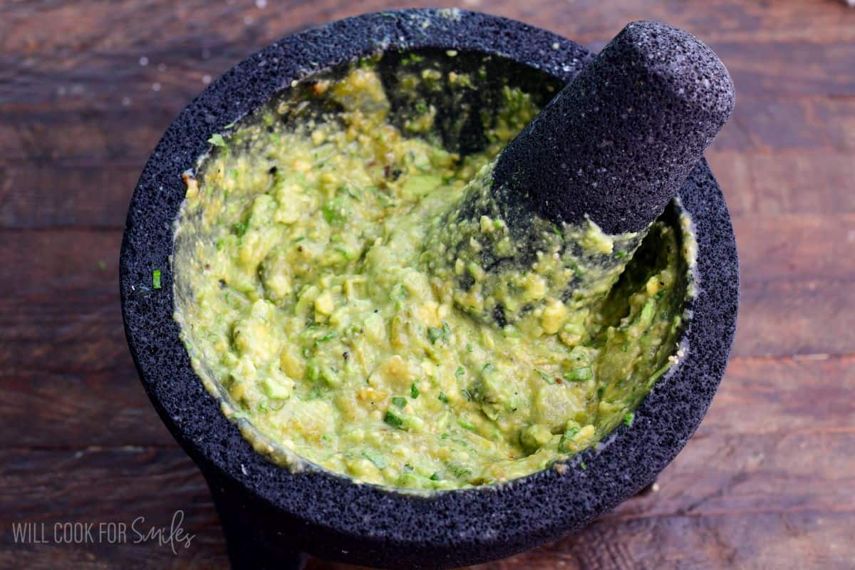 mashed avocado and green salsa in a molcajete.