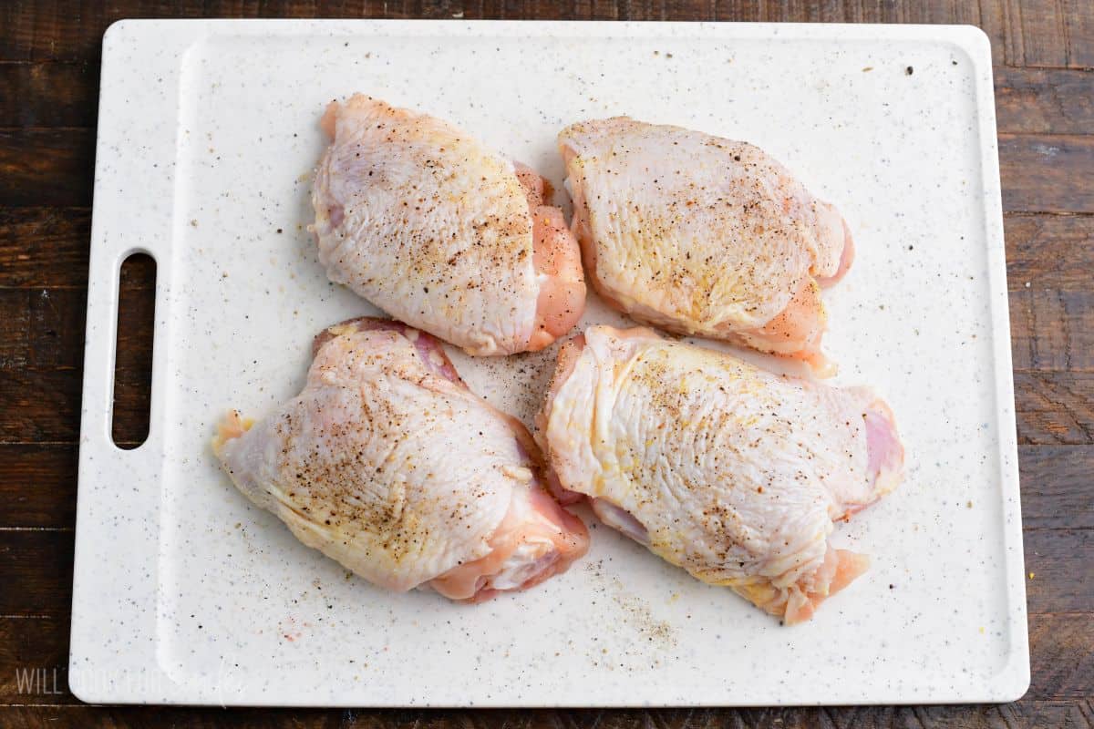 Seasoned chicken thighs arranged on a cutting board, ready to cook for baked peach chicken.