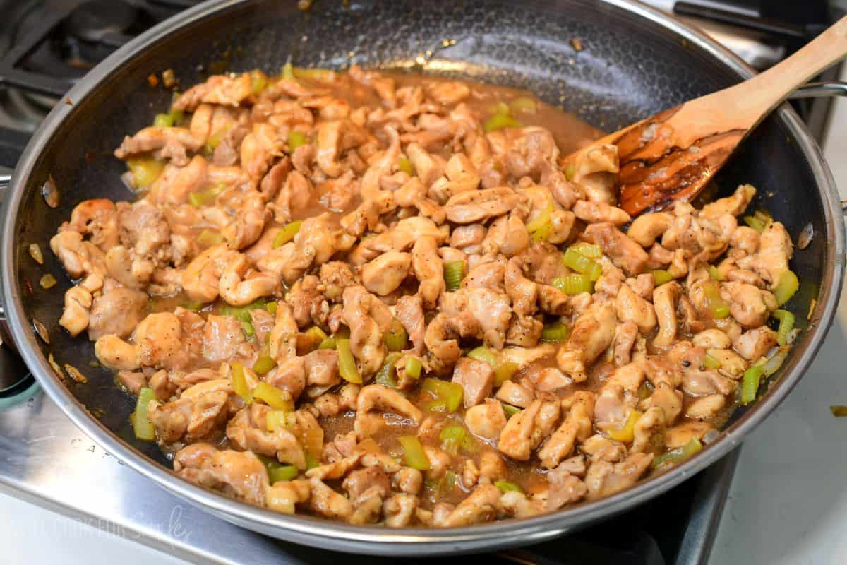Chicken simmering in pepper sauce with tender celery in a skillet before serving.