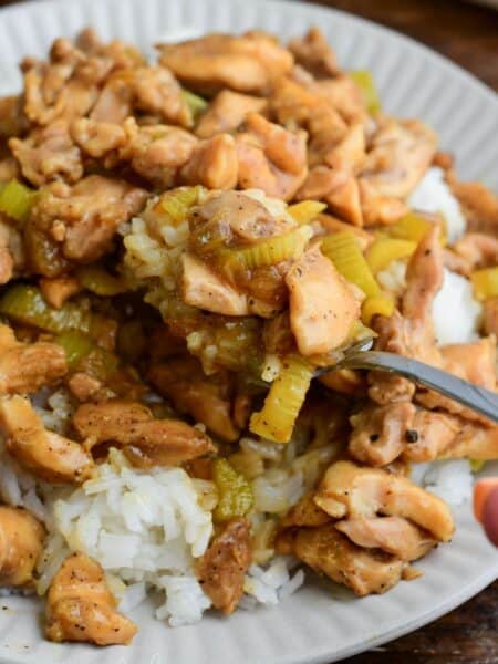 Fork lifting pepper chicken and rice with tender celery in savory sauce.