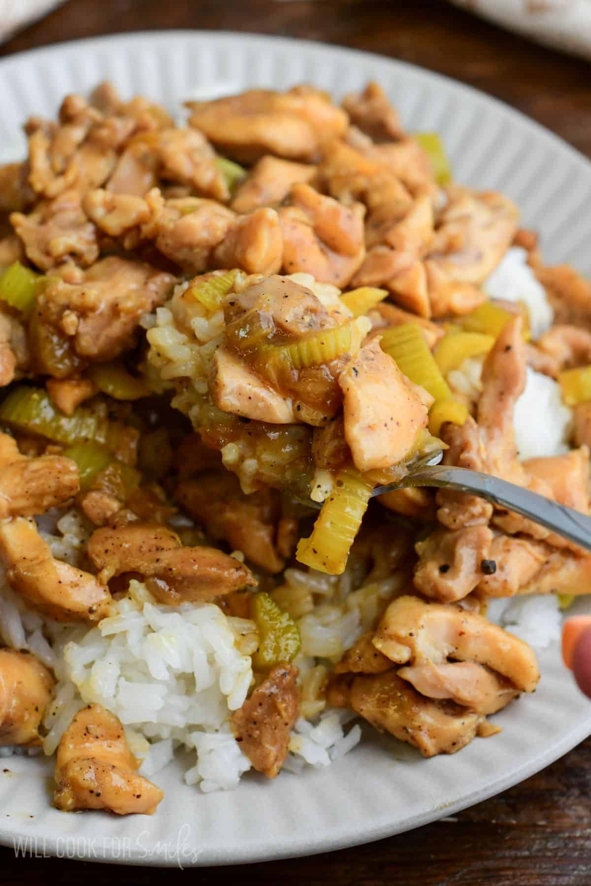 Fork lifting pepper chicken and rice with tender celery in savory sauce.
