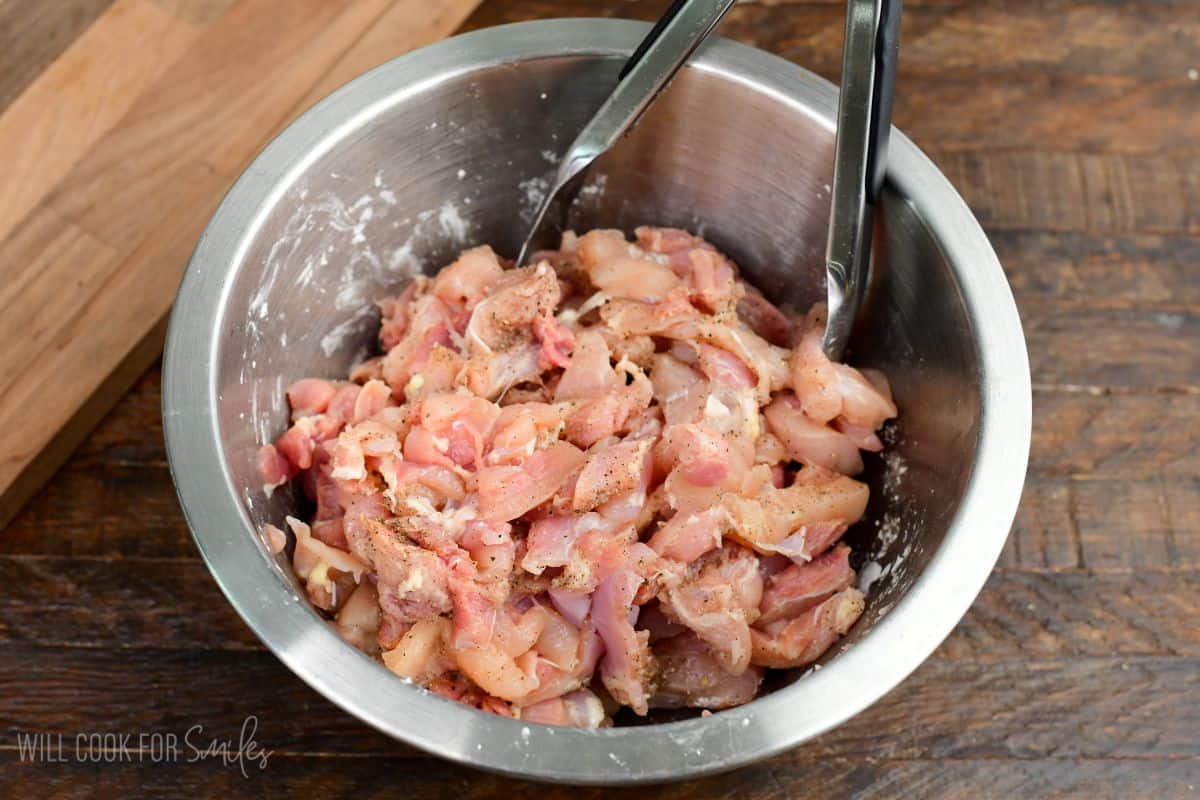 Raw chicken strips seasoned with salt and pepper in a mixing bowl, ready for stir frying.